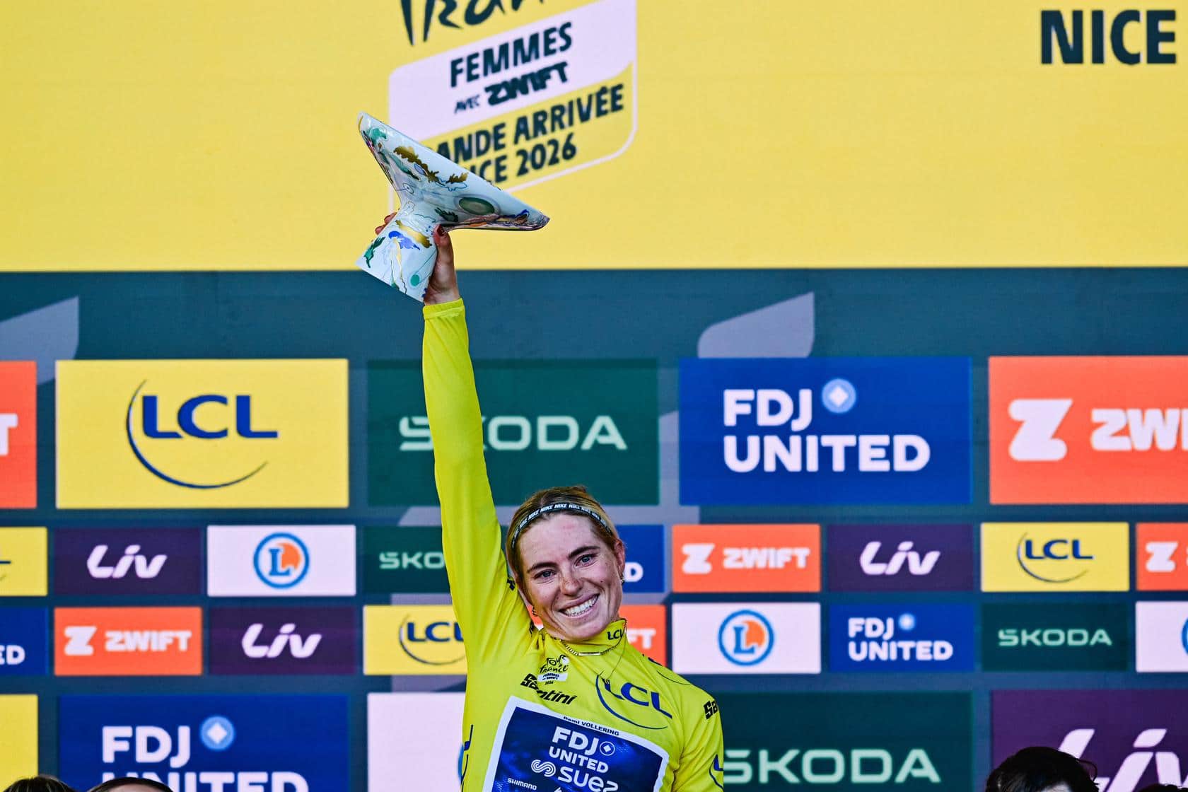 Demi Vollering eleva con su mano derecha el trofeo del Tor de Francia femenino 2026.