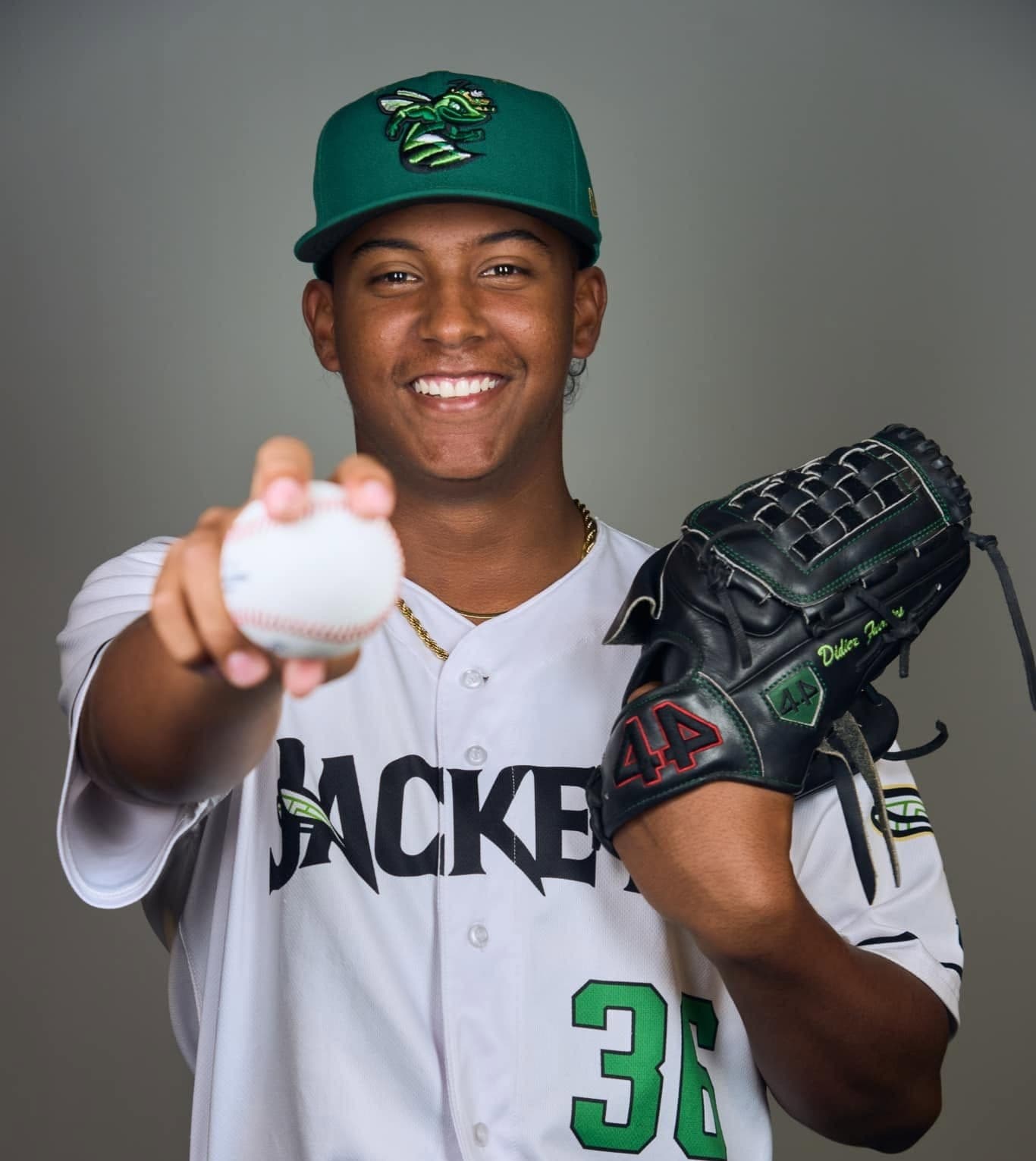 Didier Fuentes sonríe mientras sostiene una pelota con el uniforme de los Gwinnett Stripers.