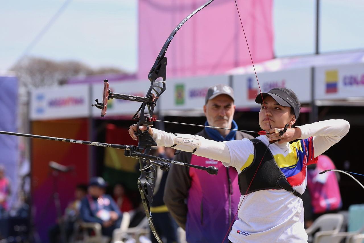 Arquera con arco de Colombia a punto de disparar.