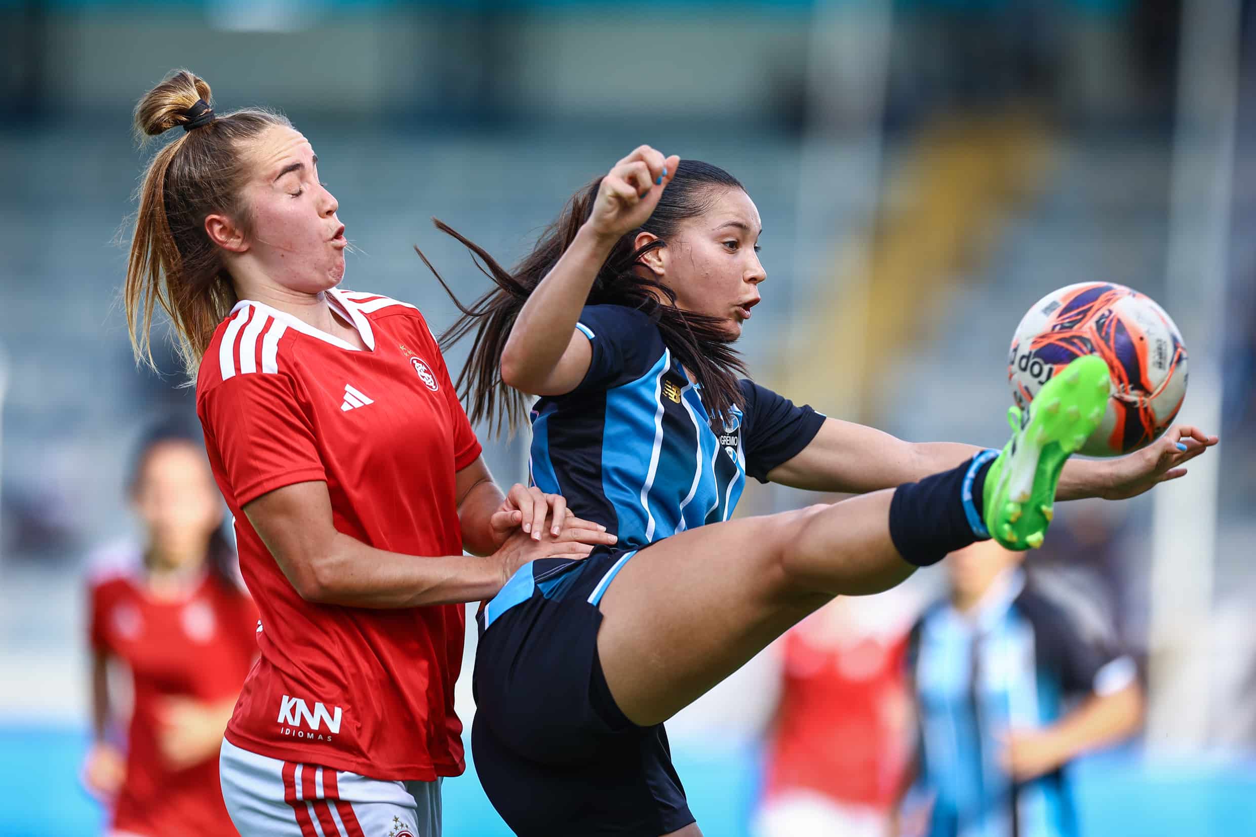Jugadoras de ambos bandos disputan un balón elevado.